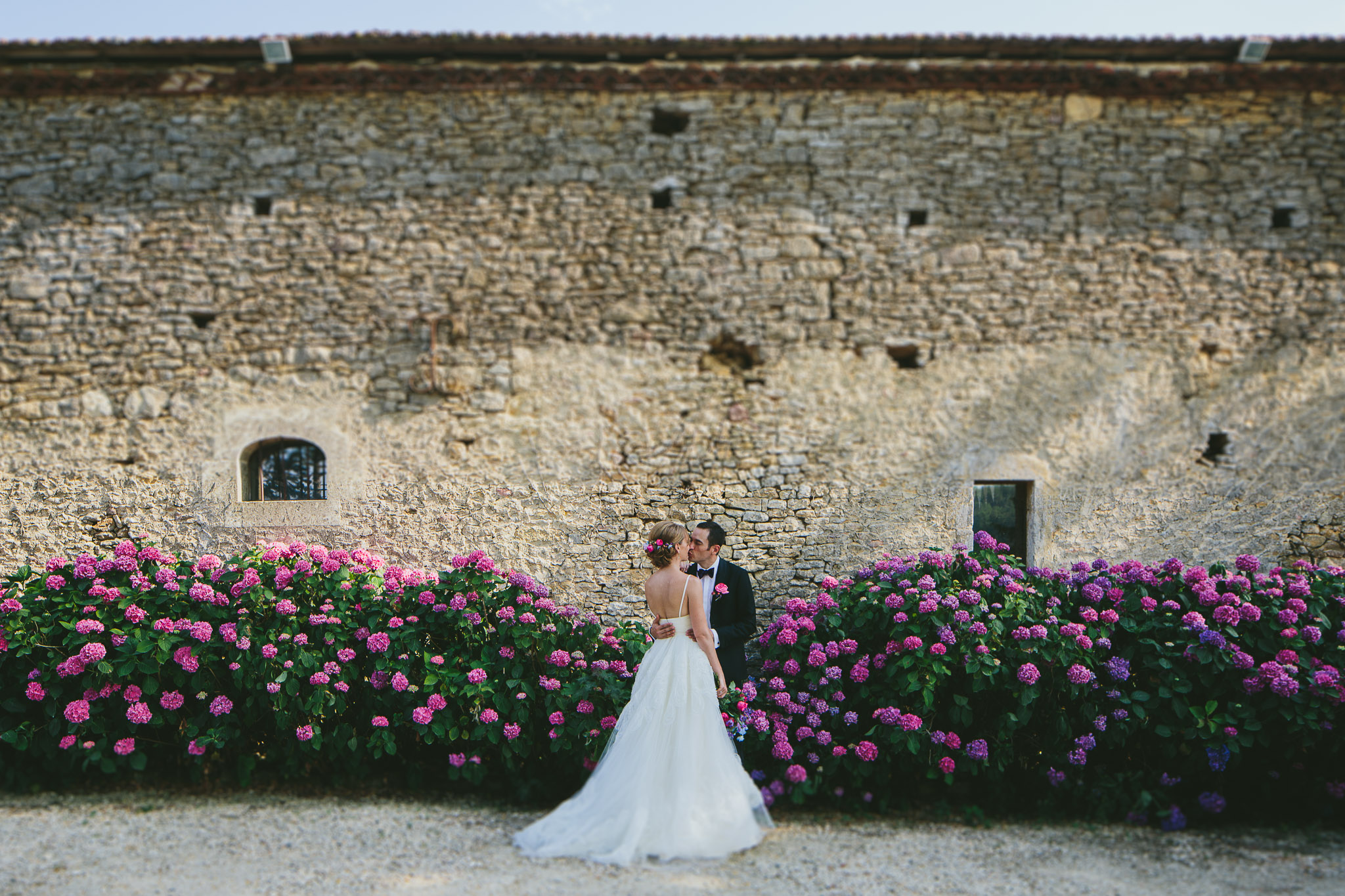 French professional wedding photographer gorgeous married couple kissing in front of a bush of hydrangeas 