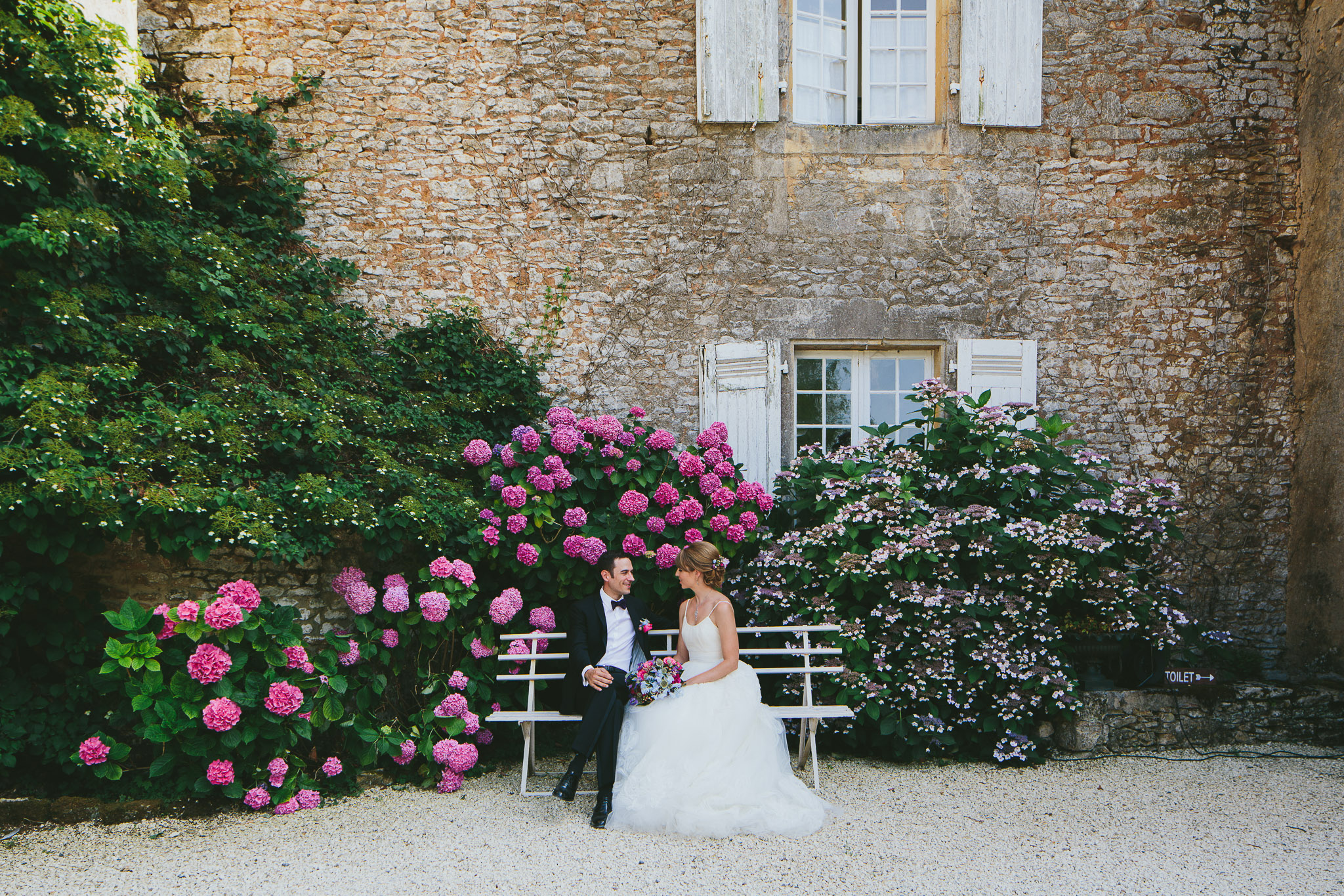 French professional wedding photographer newly weds sitting on a bench