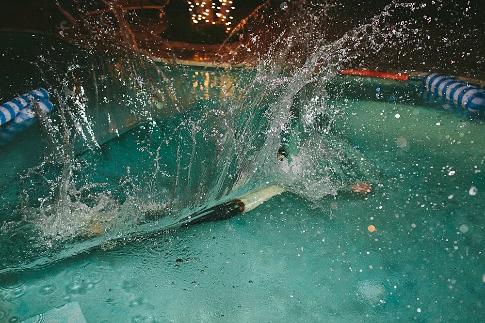 Bahamian wedding groomsman in swimming pool splash
