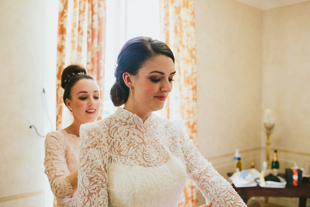 bride and bridesmaid putting on wedding dress