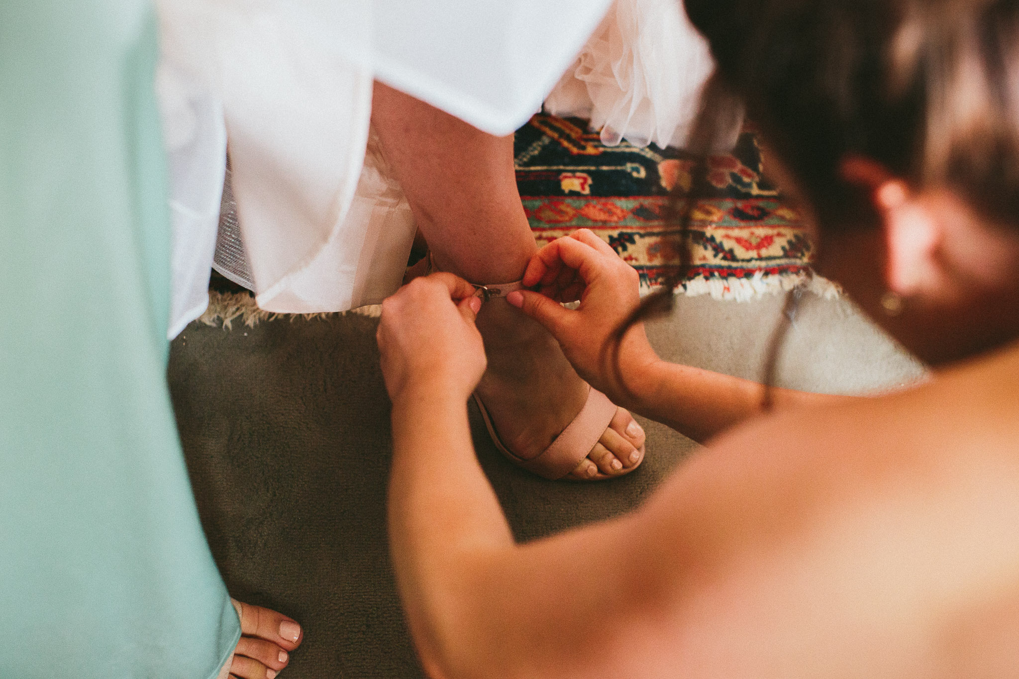 A french destination wedding bridesmaid helping bride into her wedding shoes
