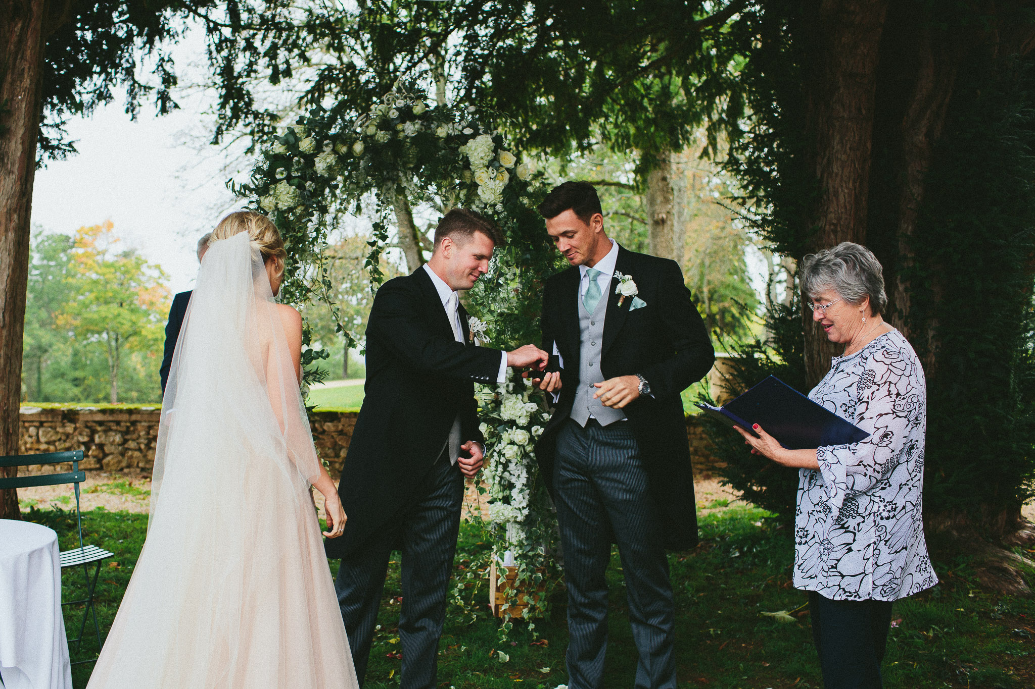 best man handing wedding rings to groom wedding ceremony