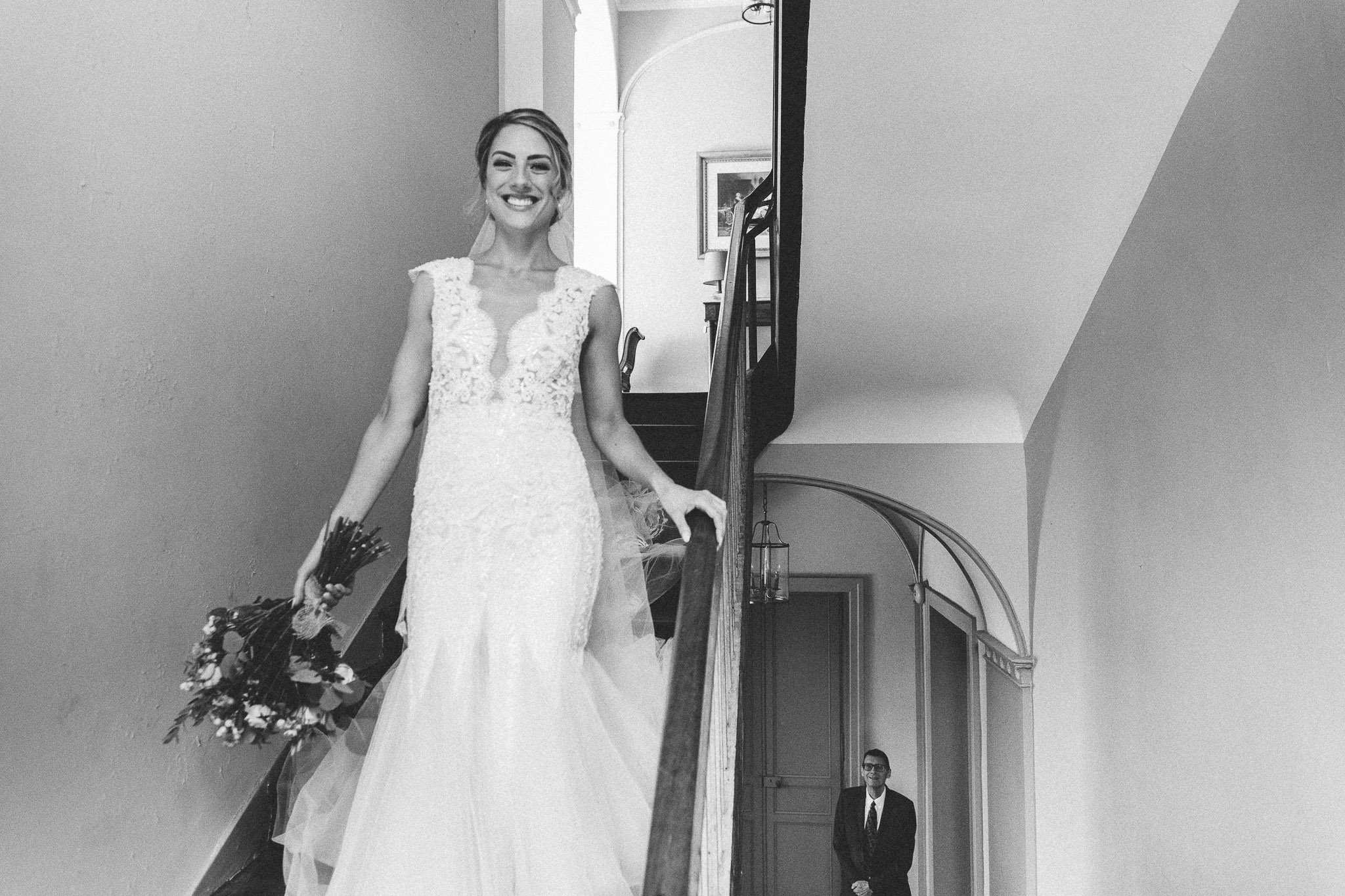 bride walking down stairs father in background