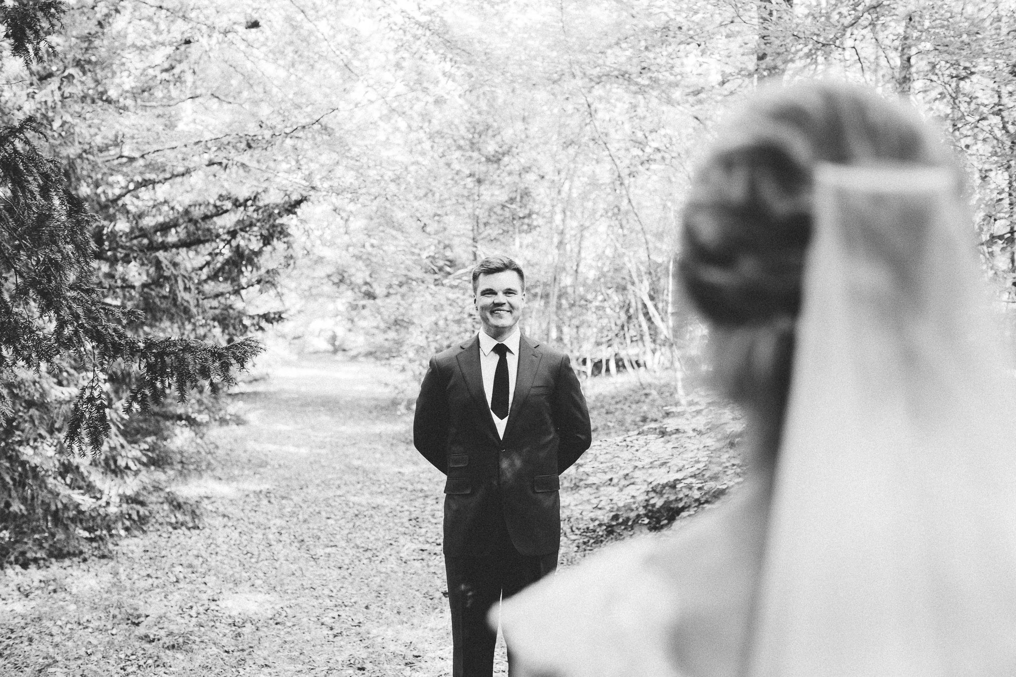 wedding photo session portrait in woods groom walking to bride smiling