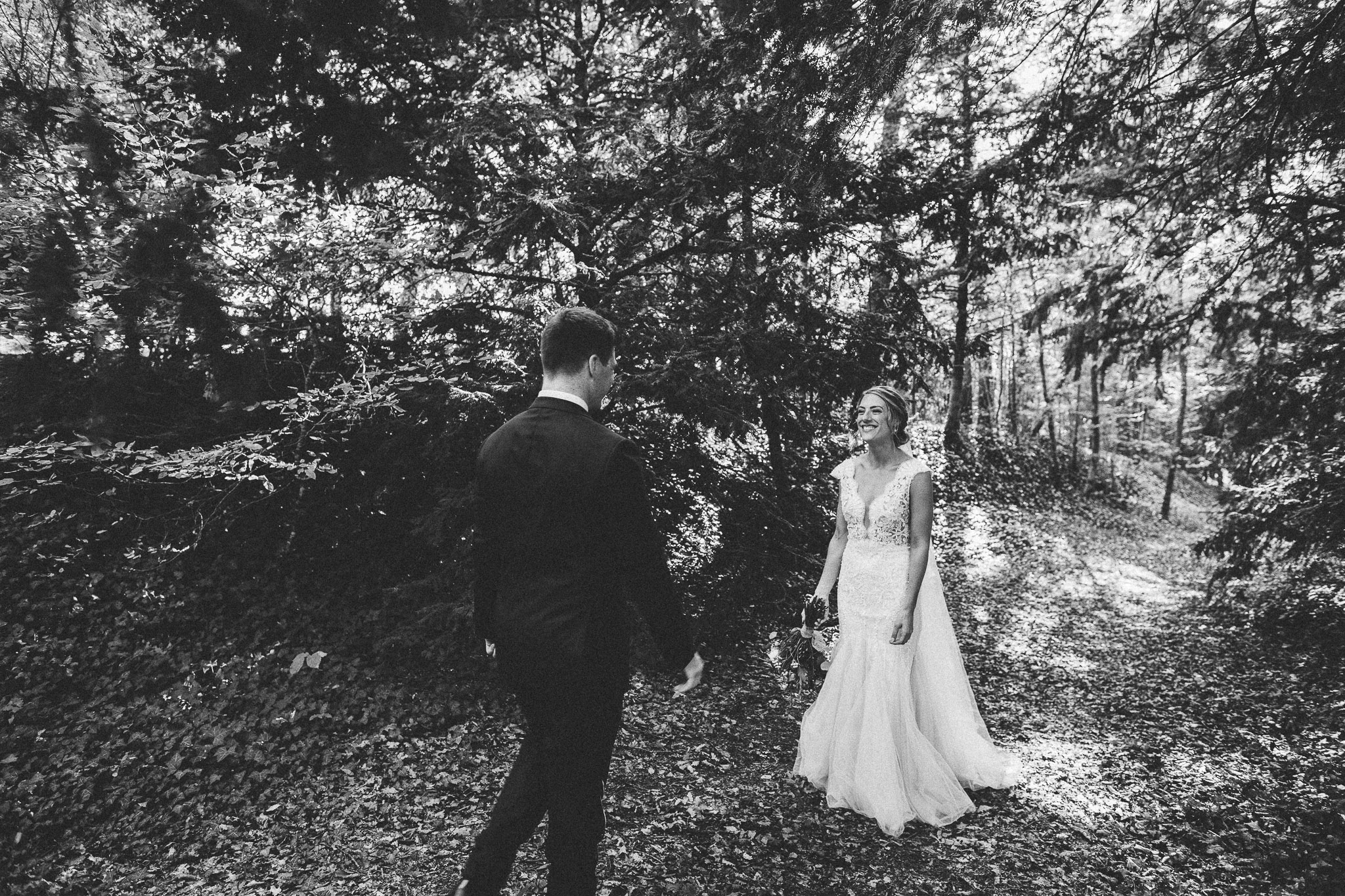 photo session portrait in woods groom walking to bride laughing