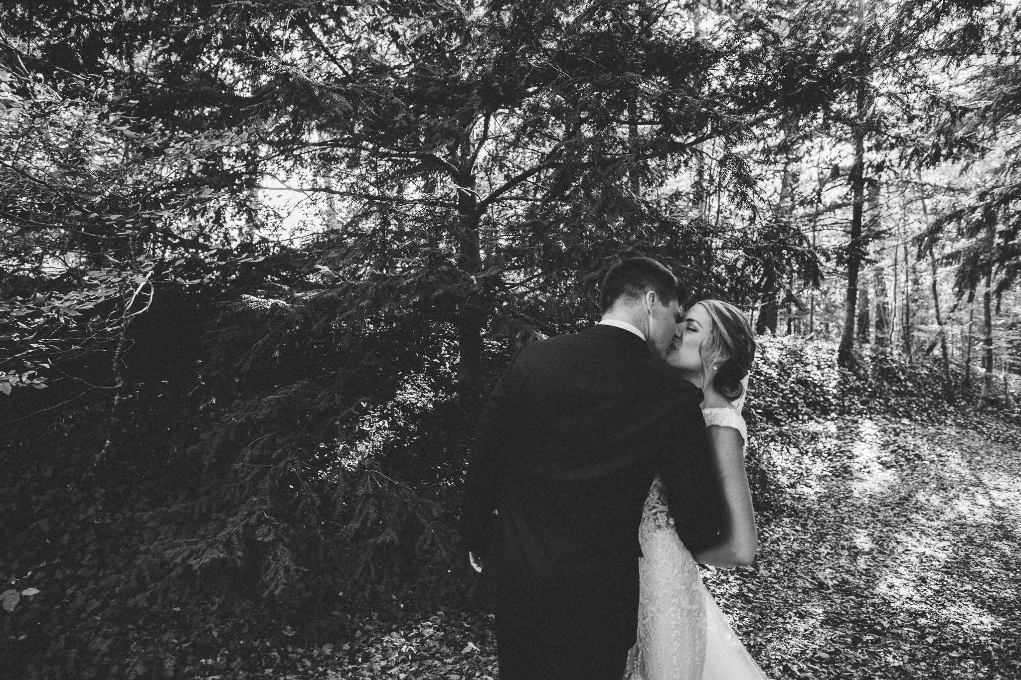 photo session portrait in woods groom walking to bride kiss