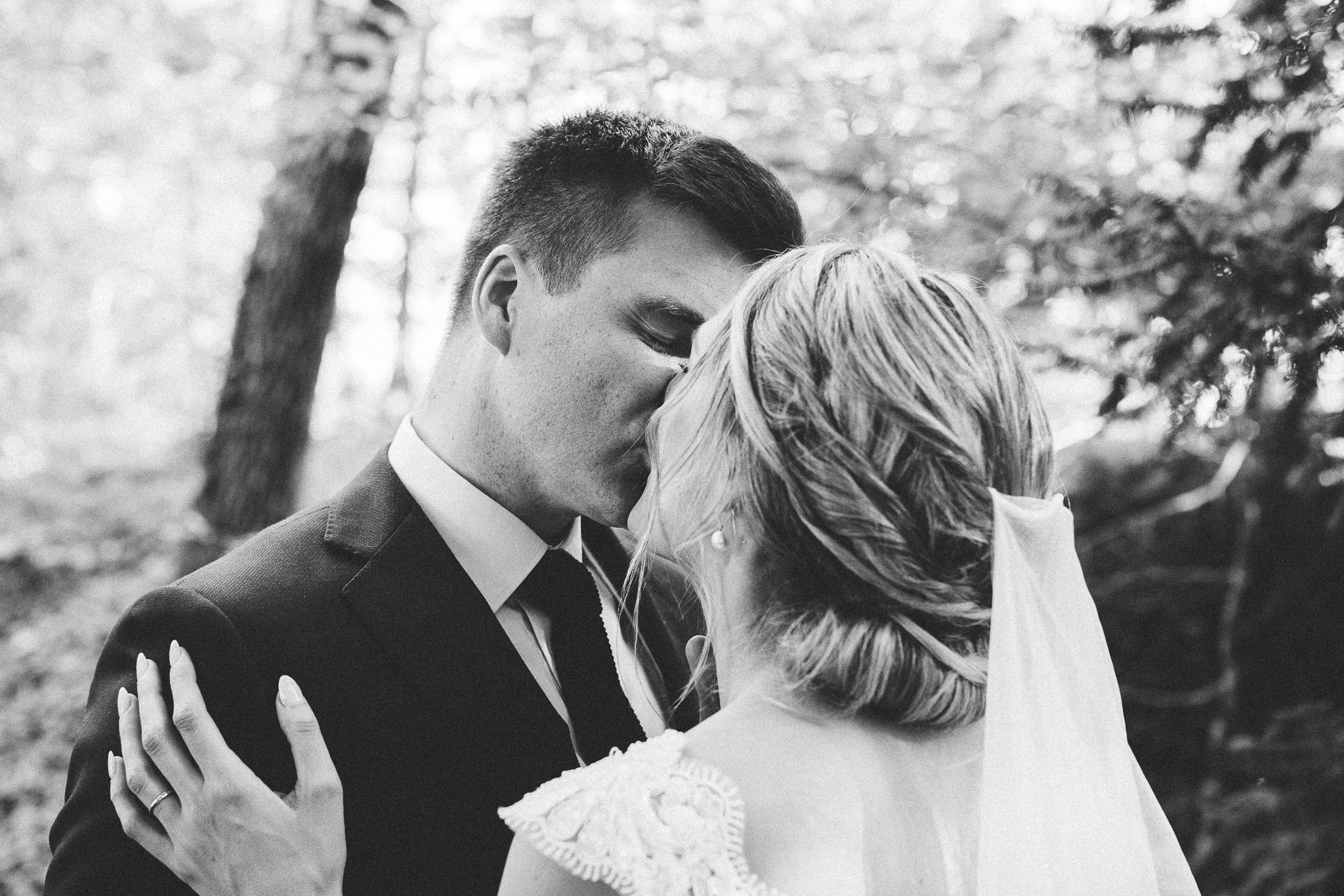 wedding photo session portrait in woods groom walking to bride kiss and hugs 