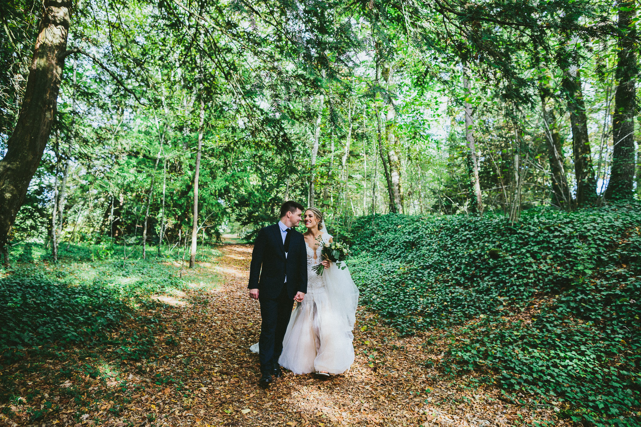 wedding photo session portrait in woods groom walking with bride