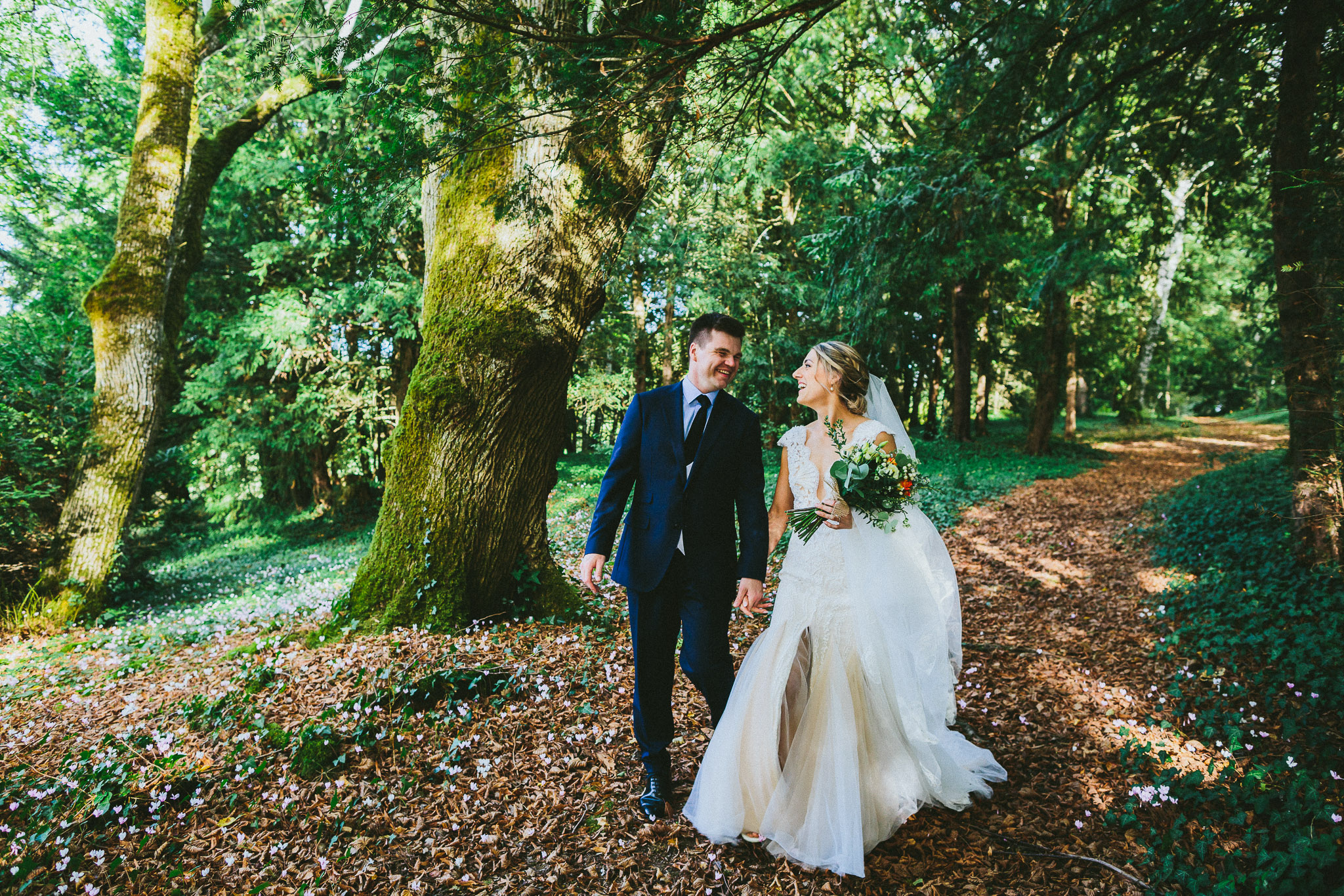 wedding photo session portrait in woods groom walking with bride laughing