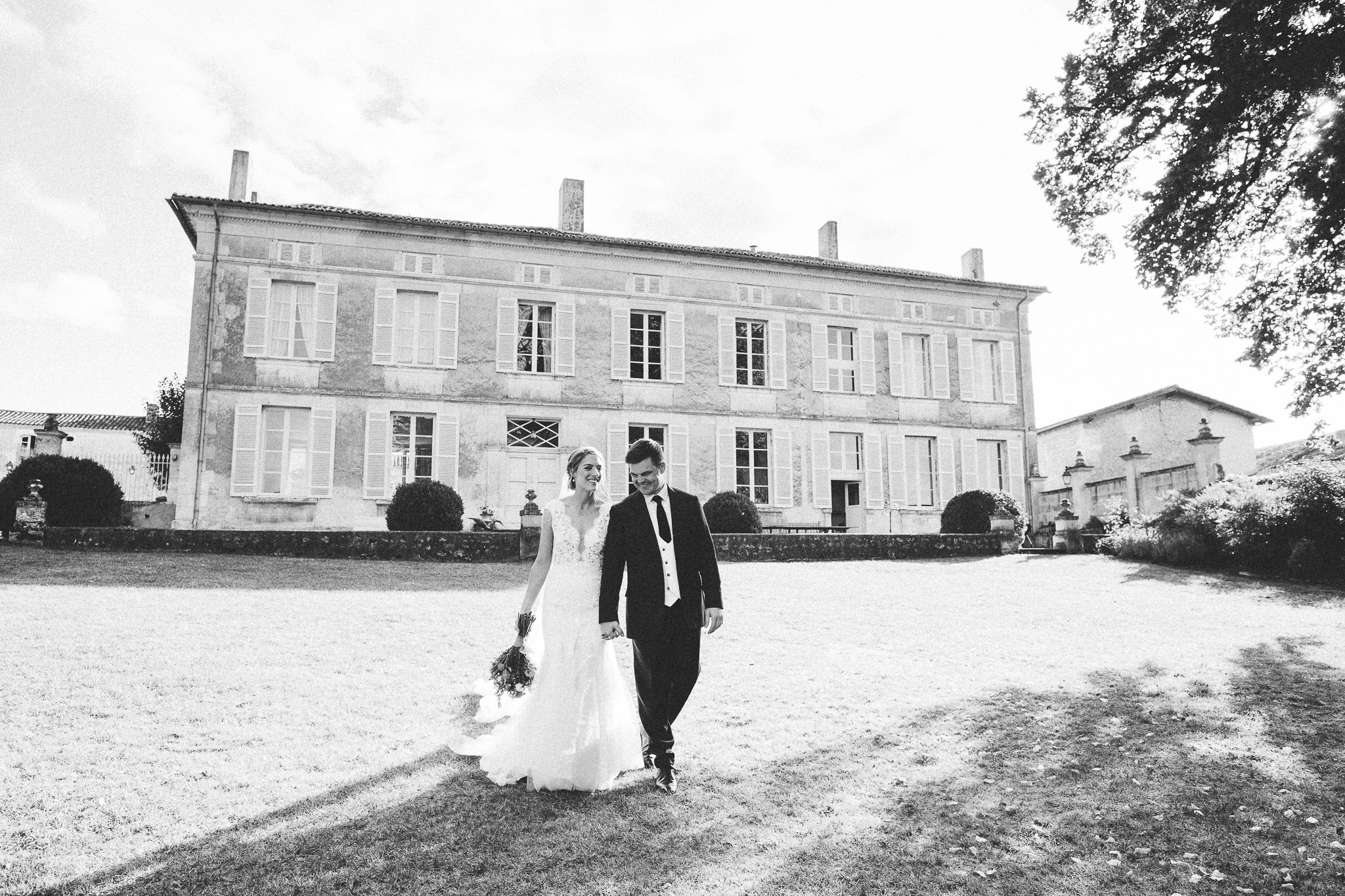 French destination wedding photo session portrait bride and groom walking french chateau in background 