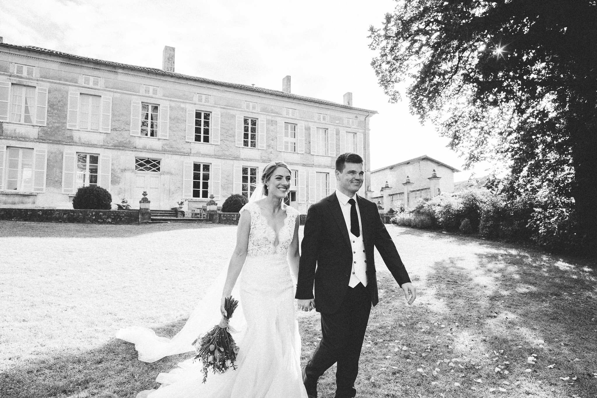 wedding photo session portrait bride and groom walking together french chateau in background 