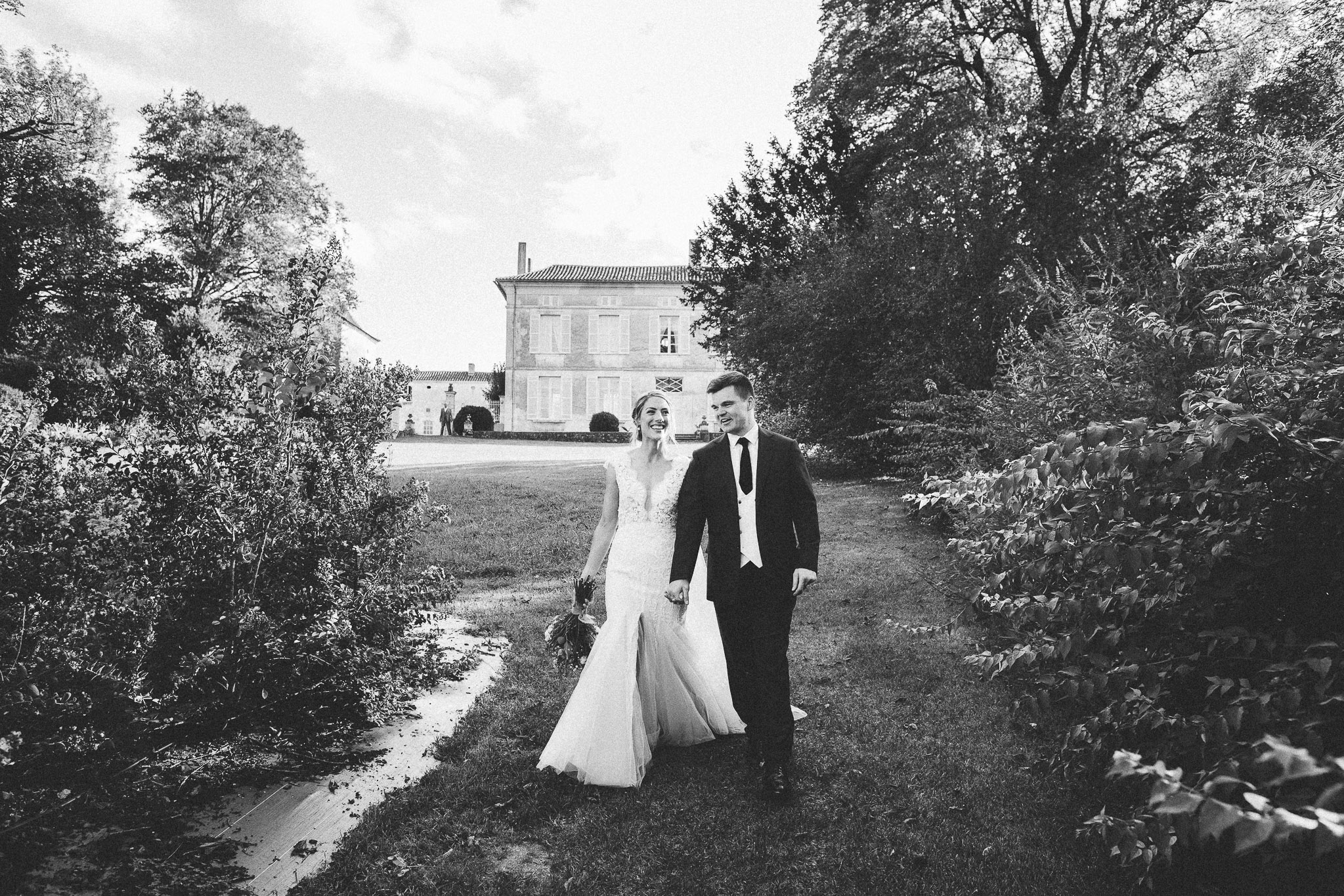 photo session portrait bride and groom laughing and walking french domaine in background 